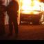 Riot police stand next to a burned out car after loyalist protesters attacked police lines in east Belfast